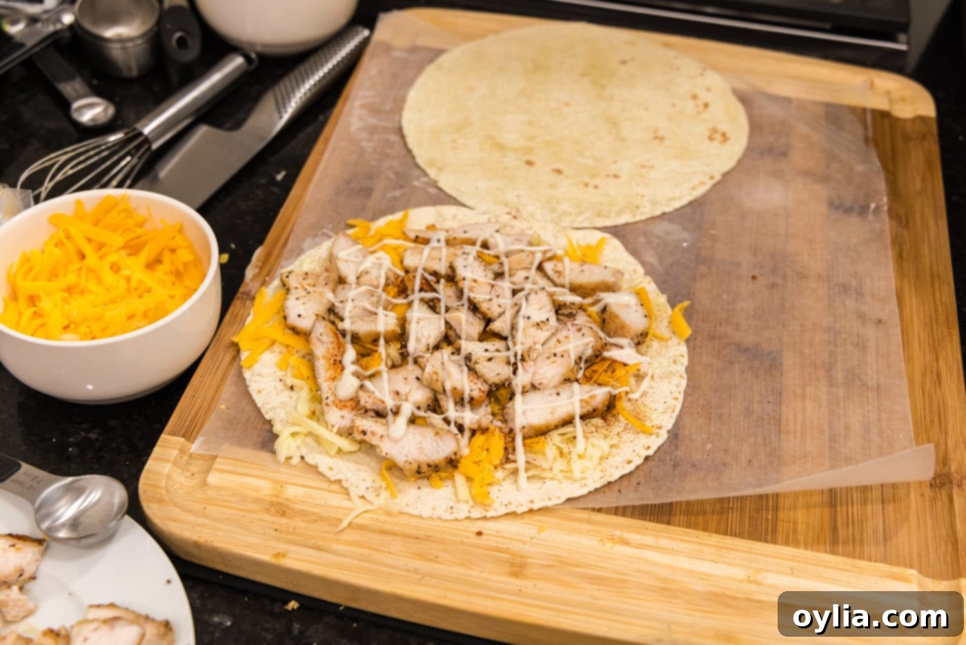 Ranch dressing drizzled over chicken and cheese on a tortilla shell