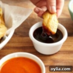 A close up photo of a crispy baked chicken wing being dipped into teriyaki sauce.