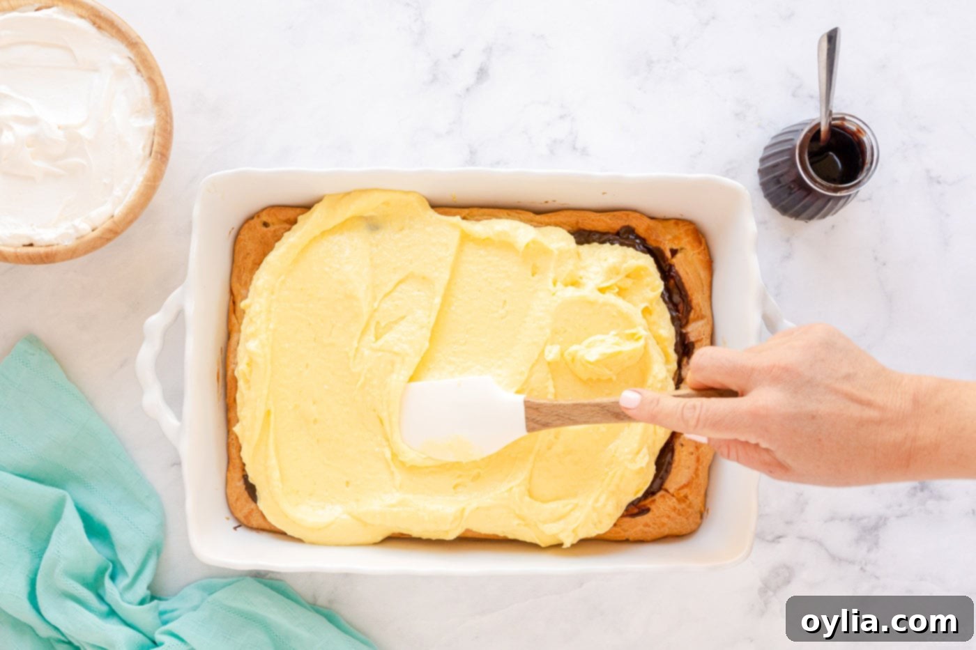 spreading pudding mixture on top of chocolate and puffy pastry