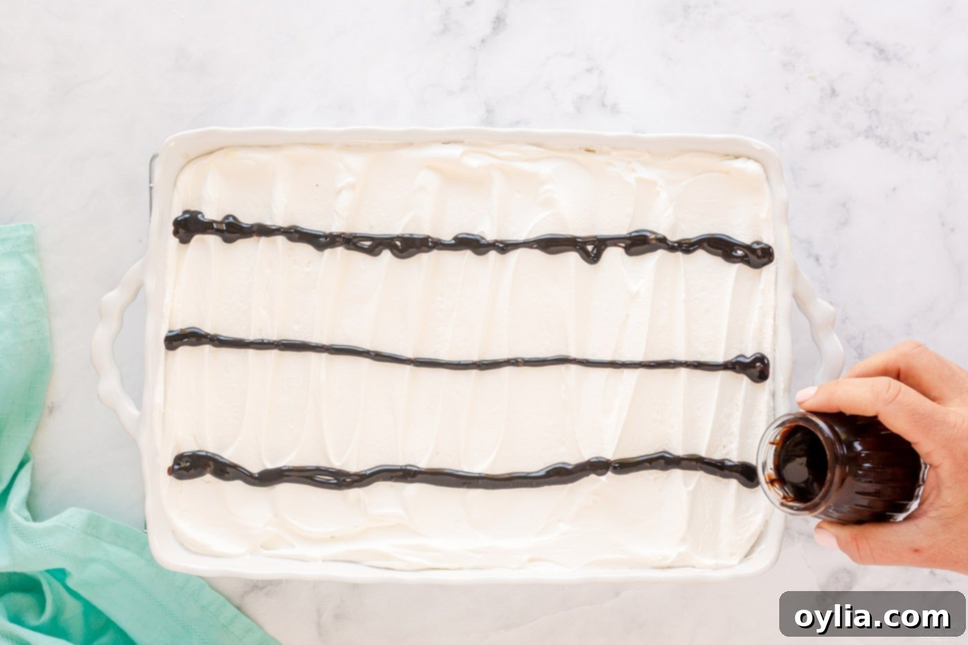 pouring lines of chocolate on top of cake