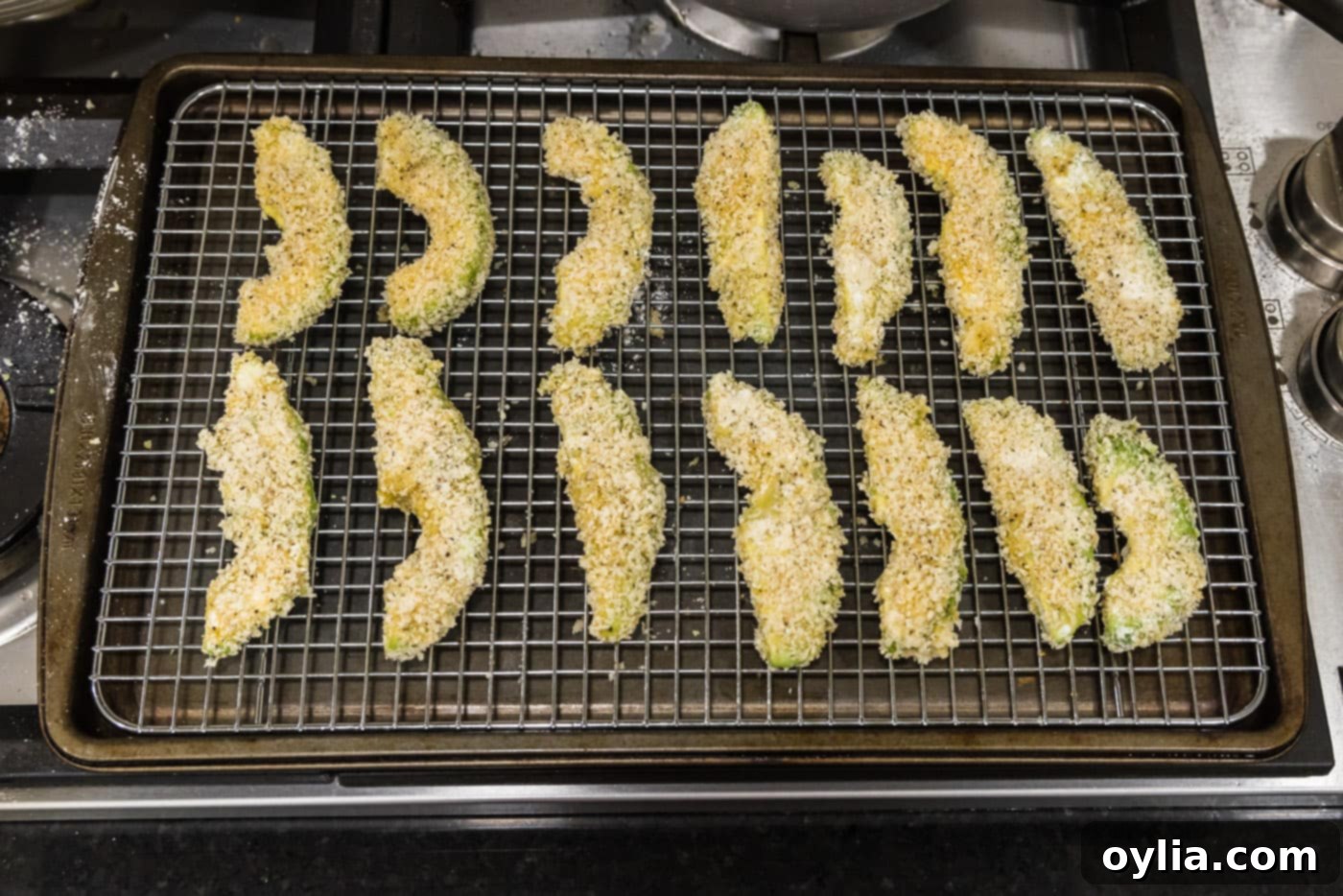Panko breadcrumb coated avocado slices neatly arranged on a wire rack