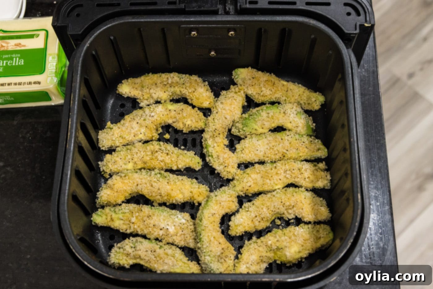 Panko coated avocado fries neatly arranged in a preheated air fryer basket