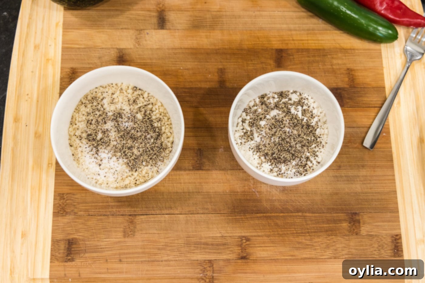 Two bowls prepared for dredging: one with seasoned breadcrumbs and the other with seasoned flour