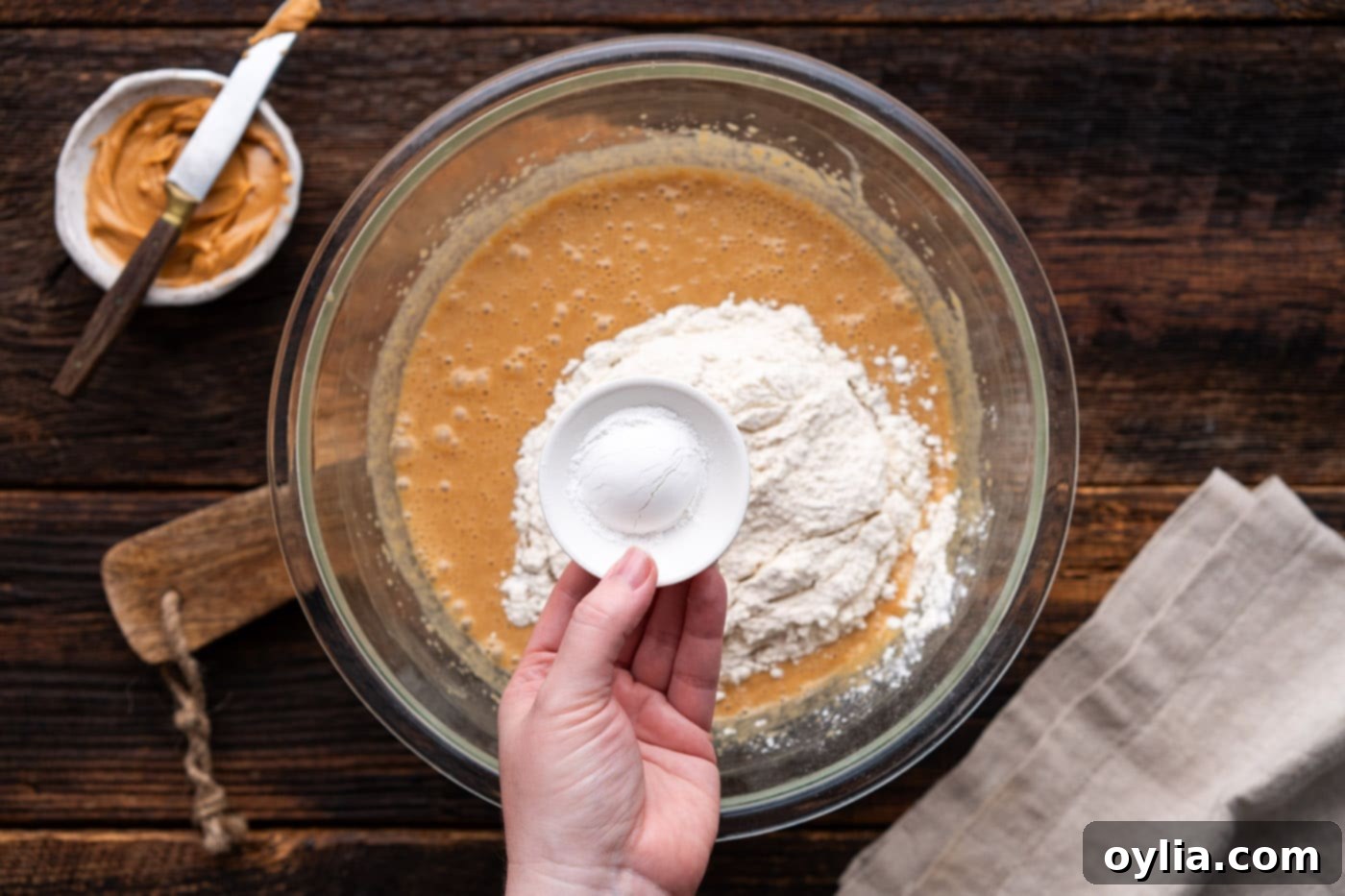 Adding all-purpose flour, baking powder, and salt to the wet peanut butter mixture.