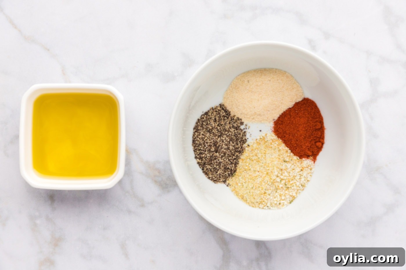 seasonings in a bowl next to a bowl of olive oil