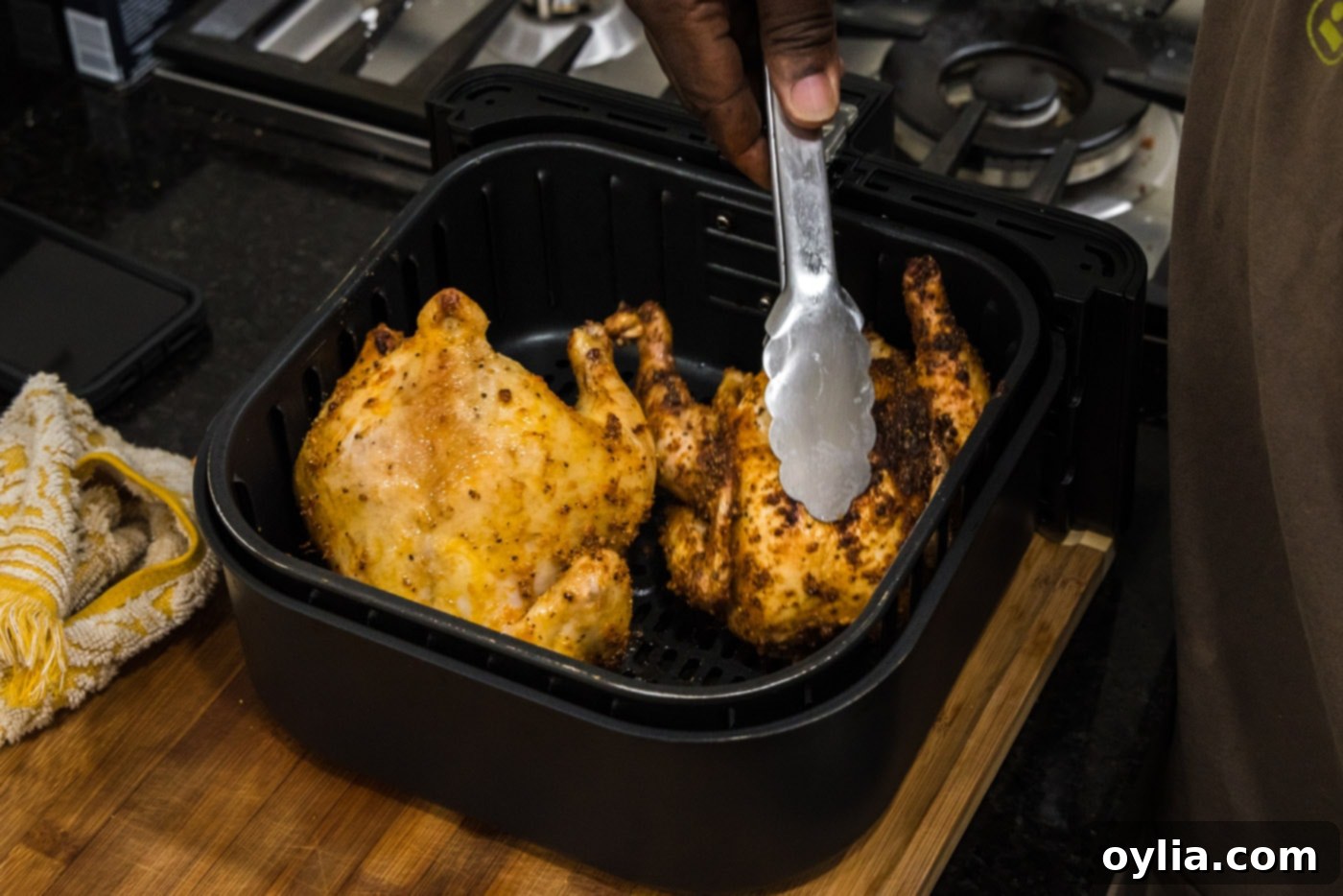 tongs flipping cornish hens over in an air fryer basket