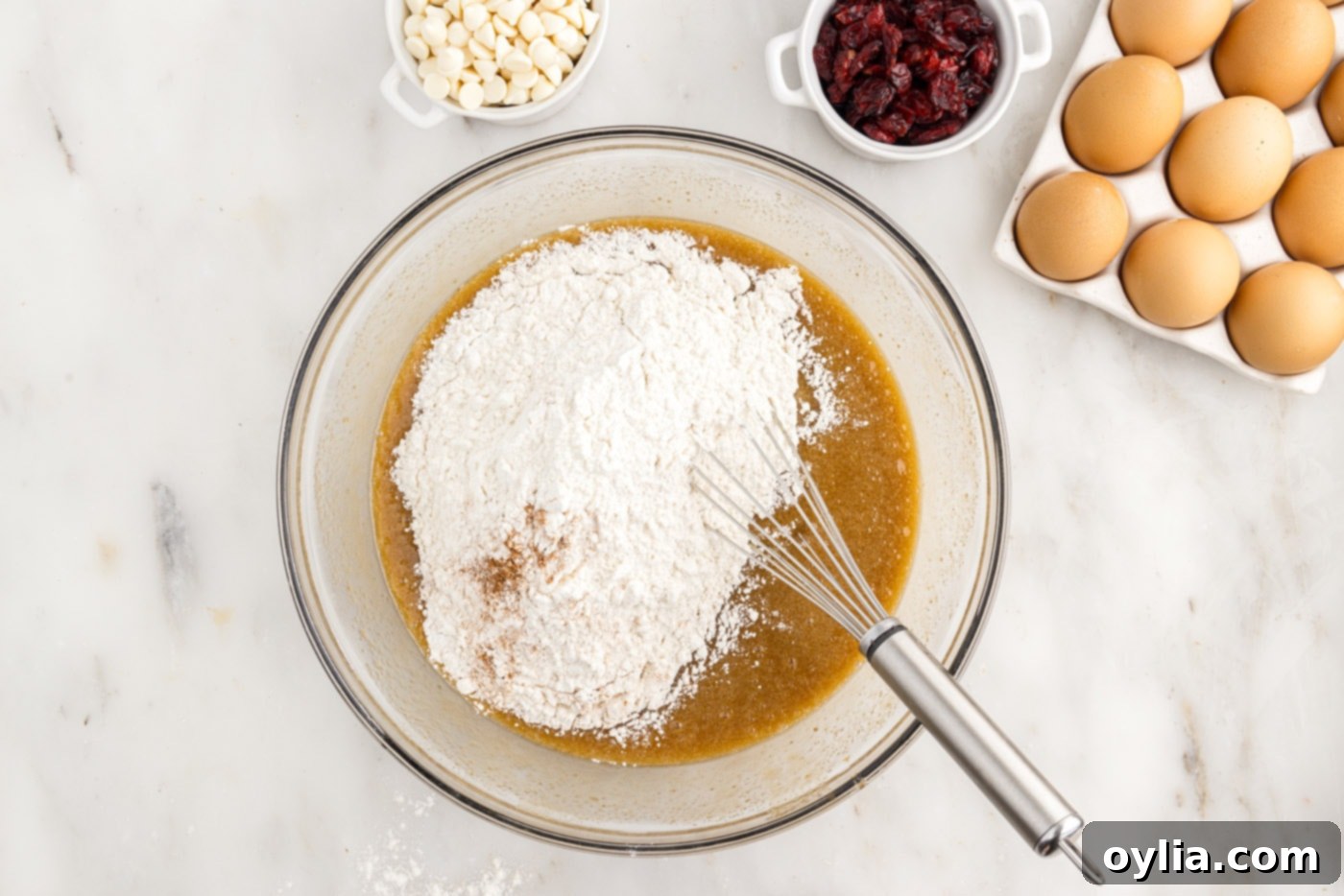 whisking flour into butter and sugar mixture in a bowl