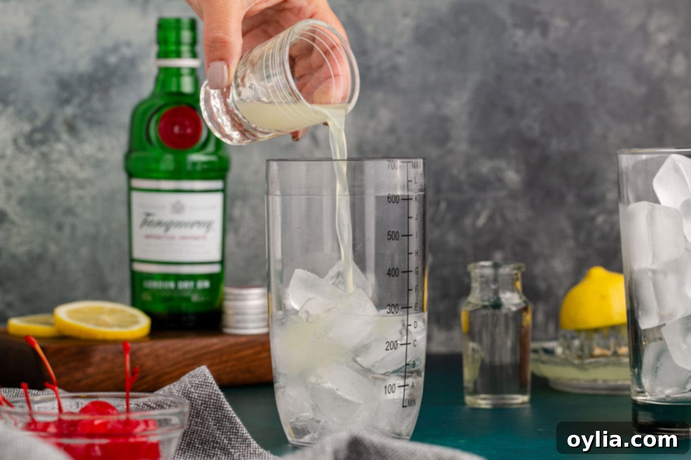 pouring fresh lemon juice over gin in cocktail shaker