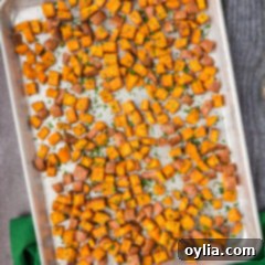 Perfectly roasted sweet potatoes with golden, crispy edges, presented on a baking sheet, ready to be enjoyed.