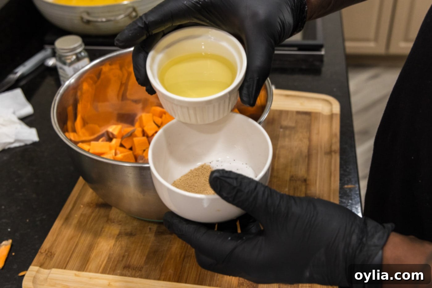 Adding rich olive oil to a bowl of aromatic spices, including brown sugar, coriander, salt, and pepper, for the sweet potato coating.