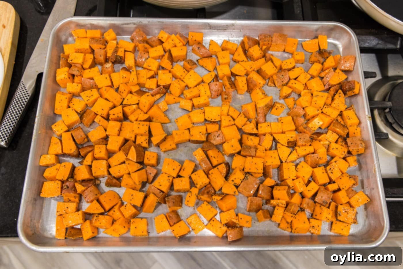 Evenly spread cubed sweet potatoes on a baking sheet, ready for roasting to achieve perfect caramelization.