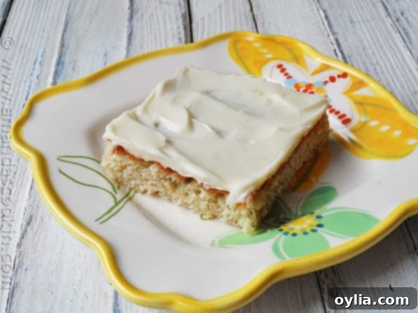 A close up photo of a banana bar with vanilla cream cheese frosting on a plate.