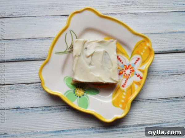 An overhead photo of a banana bar with vanilla cream cheese frosting on a plate.