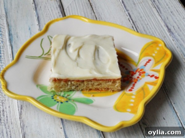 A close up photo of a banana bar with vanilla cream cheese frosting on a plate.