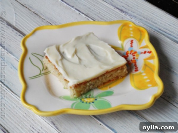 A close up photo of a banana bar with vanilla cream cheese frosting on a plate.