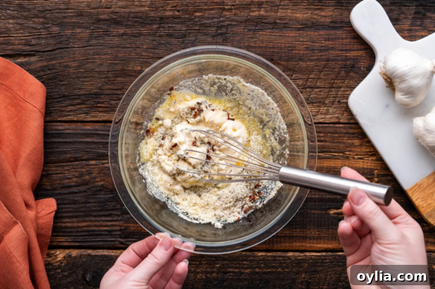 mixing parmesan garlic wing sauce ingredients in a bowl with a whisk
