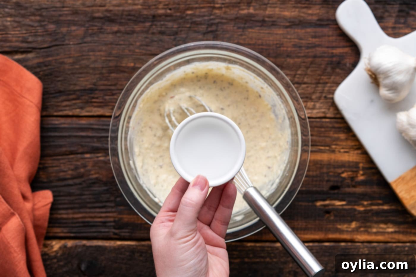 adding water to a bowl of wing sauce ingredients to adjust consistency