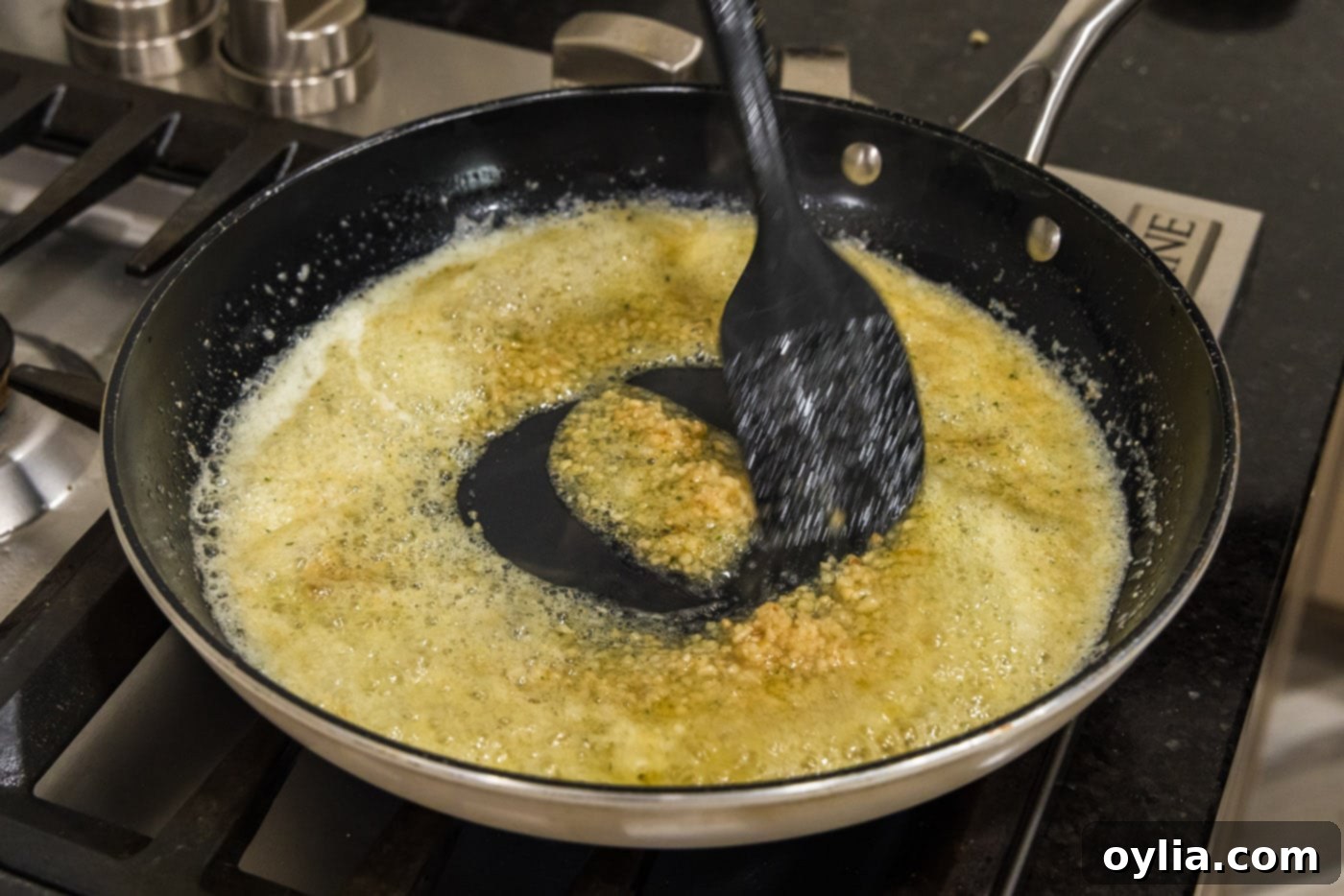 Stirring minced garlic into the seasoned, bubbly butter in a skillet to make the wing sauce.