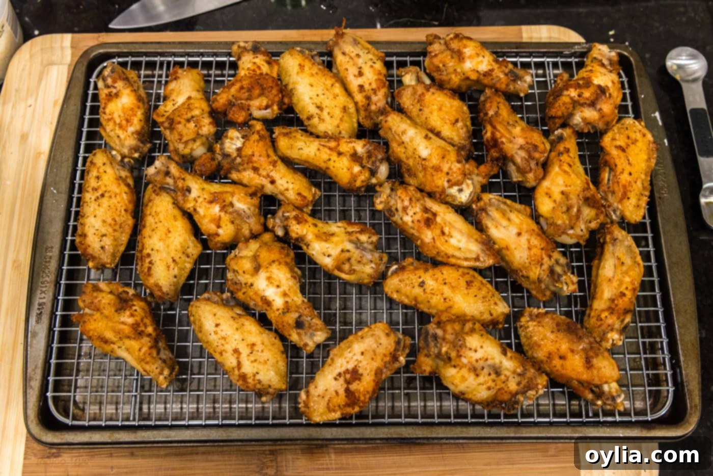 Crispy fried chicken wings draining on a wire rack to remove excess oil.