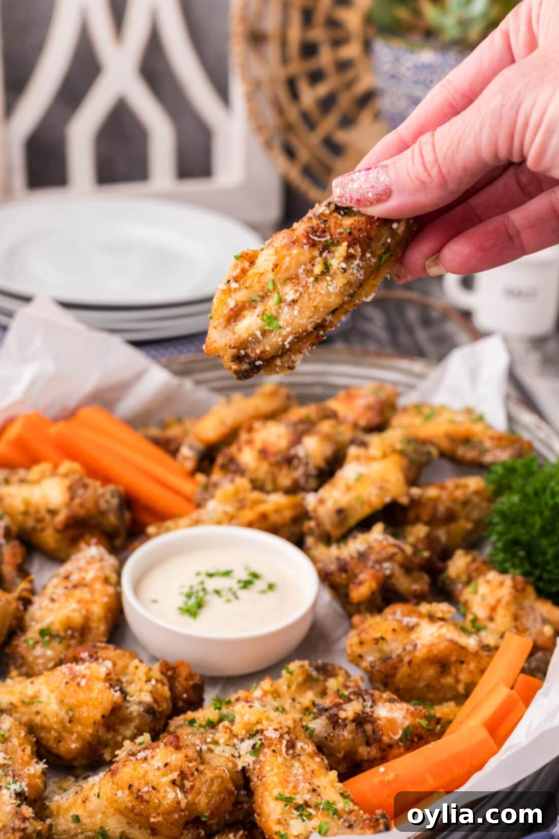 A hand holding up a single Garlic Parmesan Wing, glistening with sauce and showing its crispy texture.