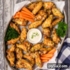 Serving tray of Garlic Parmesan Wings with a bowl of dipping sauce in the center, garnished with fresh herbs.