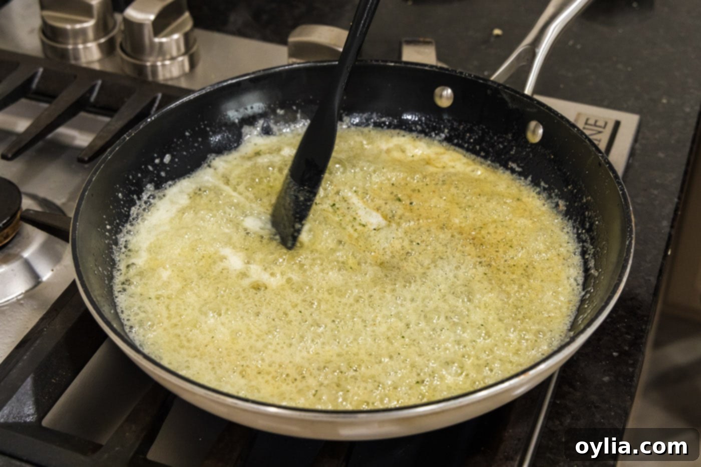 Melted butter in a skillet, bubbling gently after seasonings have been added and stirred.