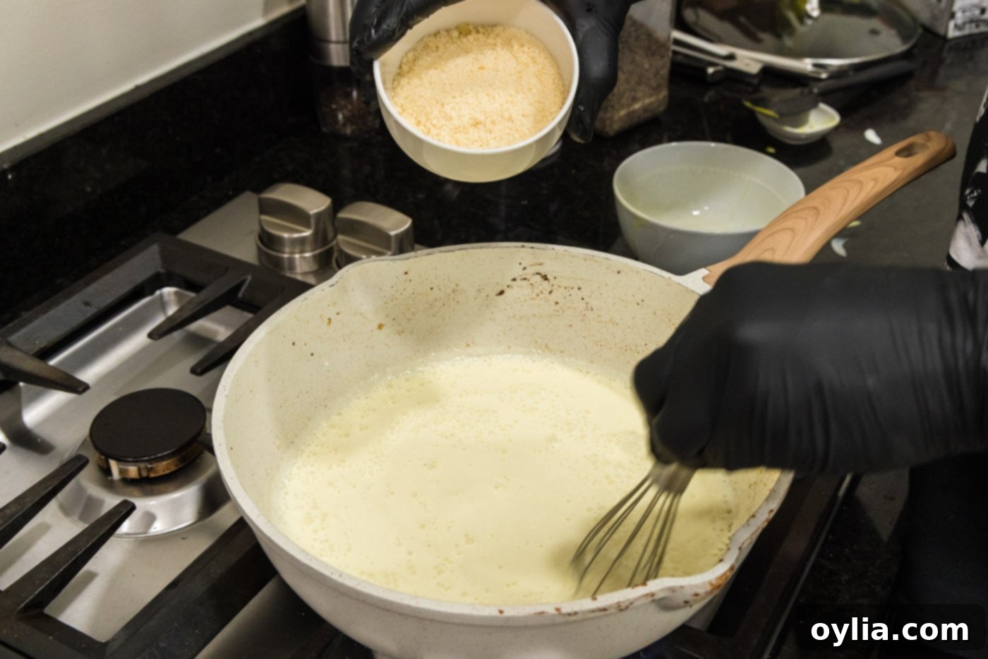 adding parmesan cheese to heavy cream and egg mixture in a skillet