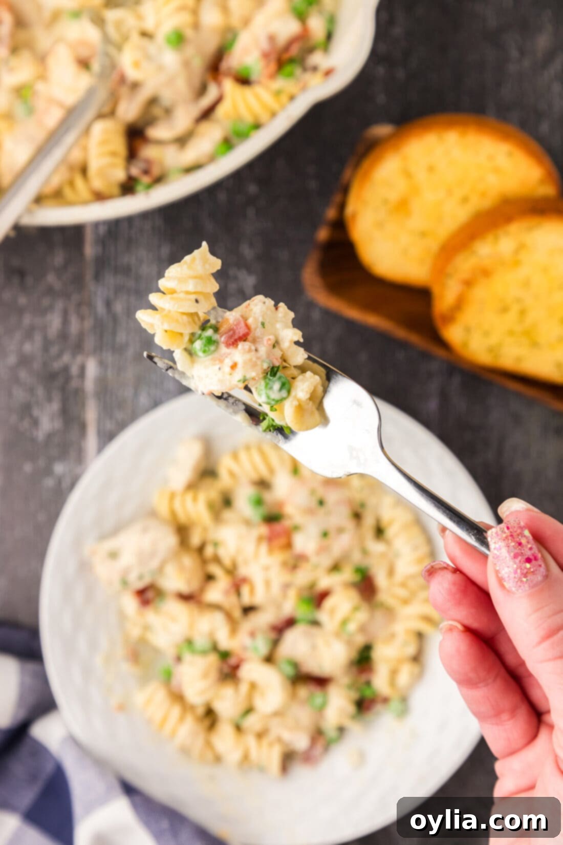 Chicken and Shrimp Carbonara on a fork held above a bowl of Chicken and Shrimp Carbonara
