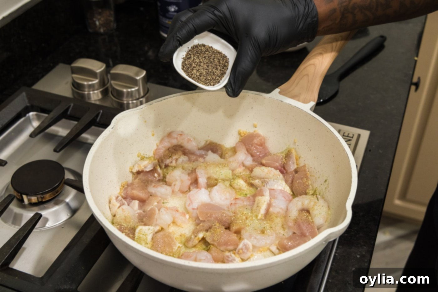 adding seasoning to skillet of shrimp, chicken, and garlic.