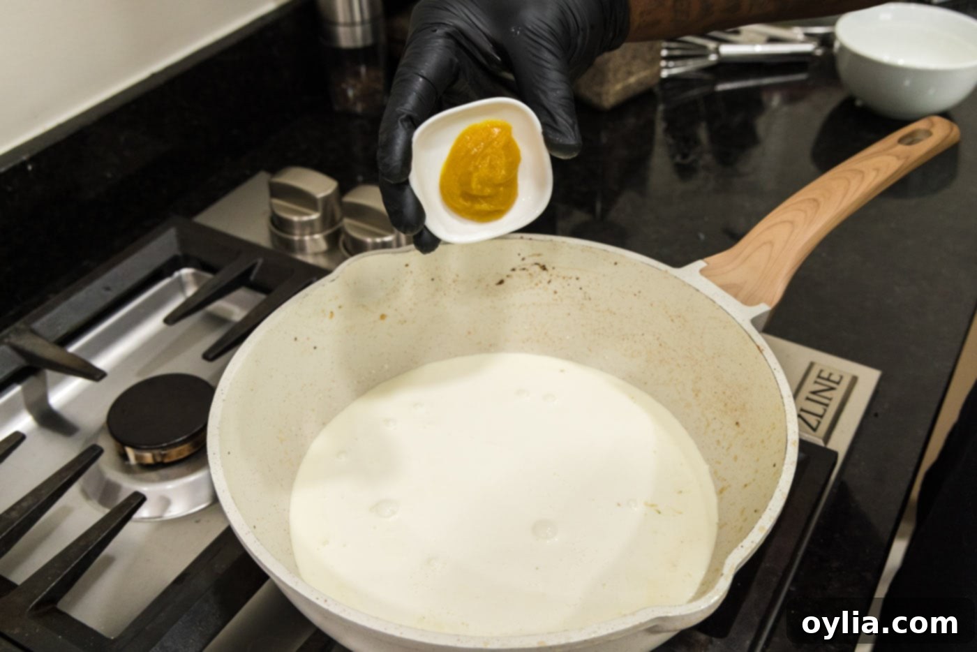 adding chicken base to skillet of heavy cream