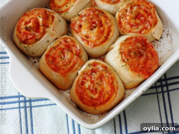 A close-up of a plate filled with freshly baked, golden pizza roll ups, steam gently rising, ready to be enjoyed.