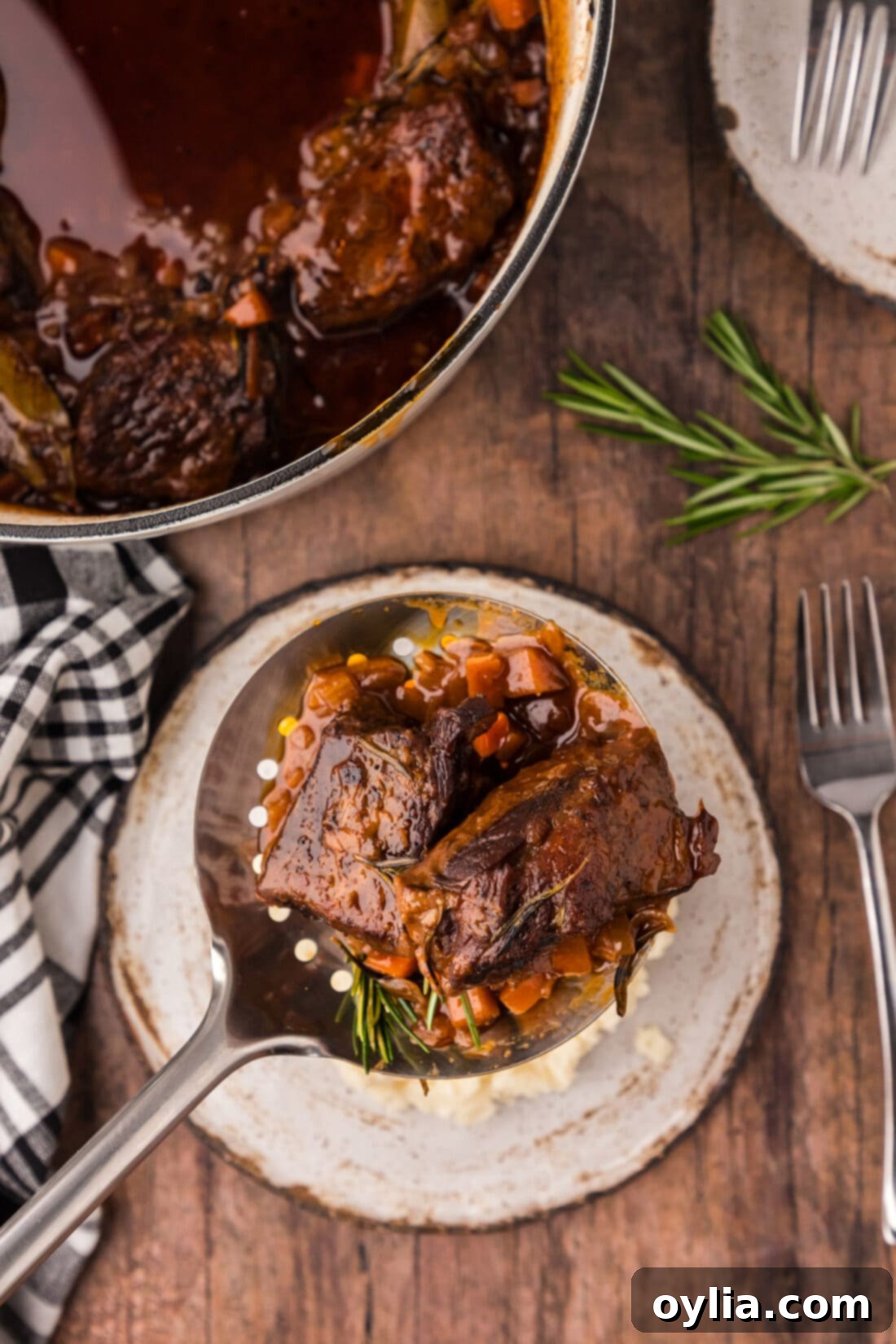 A spoon lifting a piece of tender braised beef short rib, showcasing its succulence and rich color.