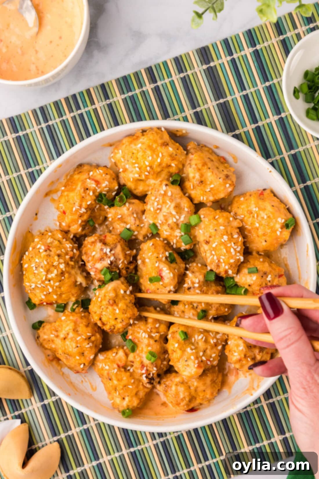 Chopsticks grabbing a piece of Bang Bang Cauliflower off a plate