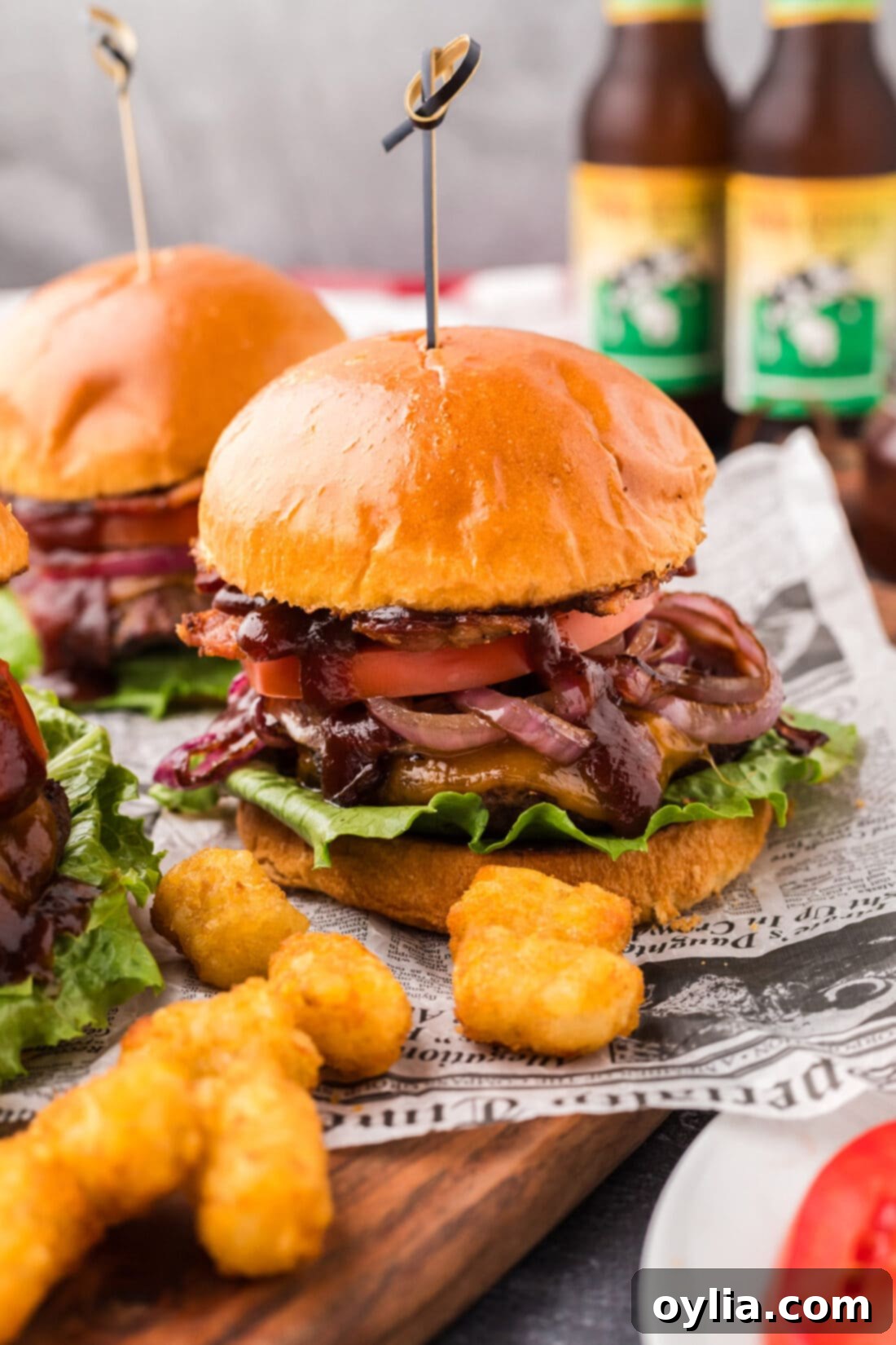 BBQ Bacon Burgers on a wooden board with tater tots