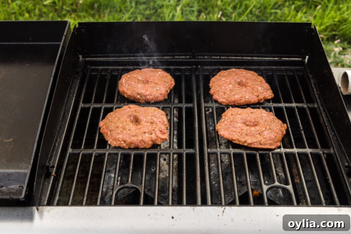 burger patties cooking on a grill grate