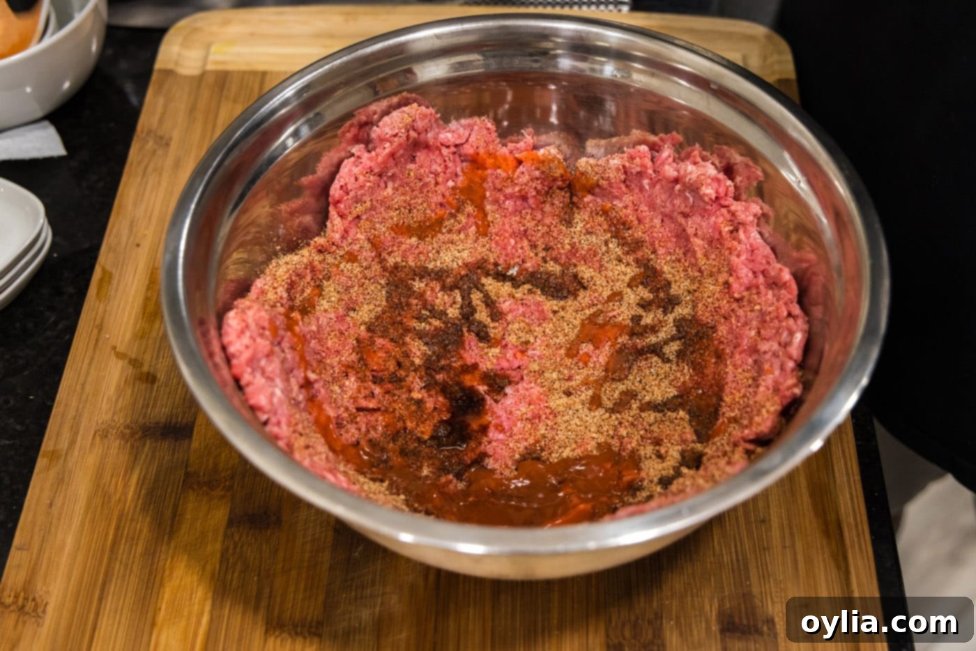 mixing burger meat with seasonings in a bowl