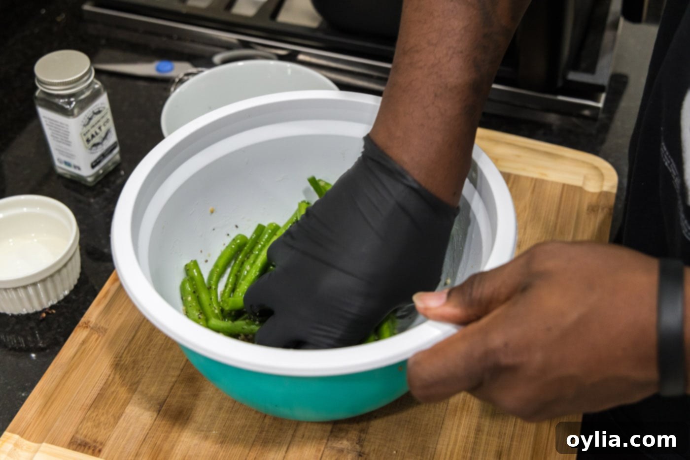 hand tossing green beans with seasonings in a bowl