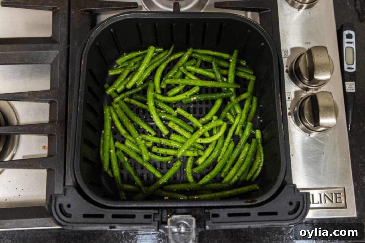 fresh green beans with seasoning and garlic in an air fryer basket