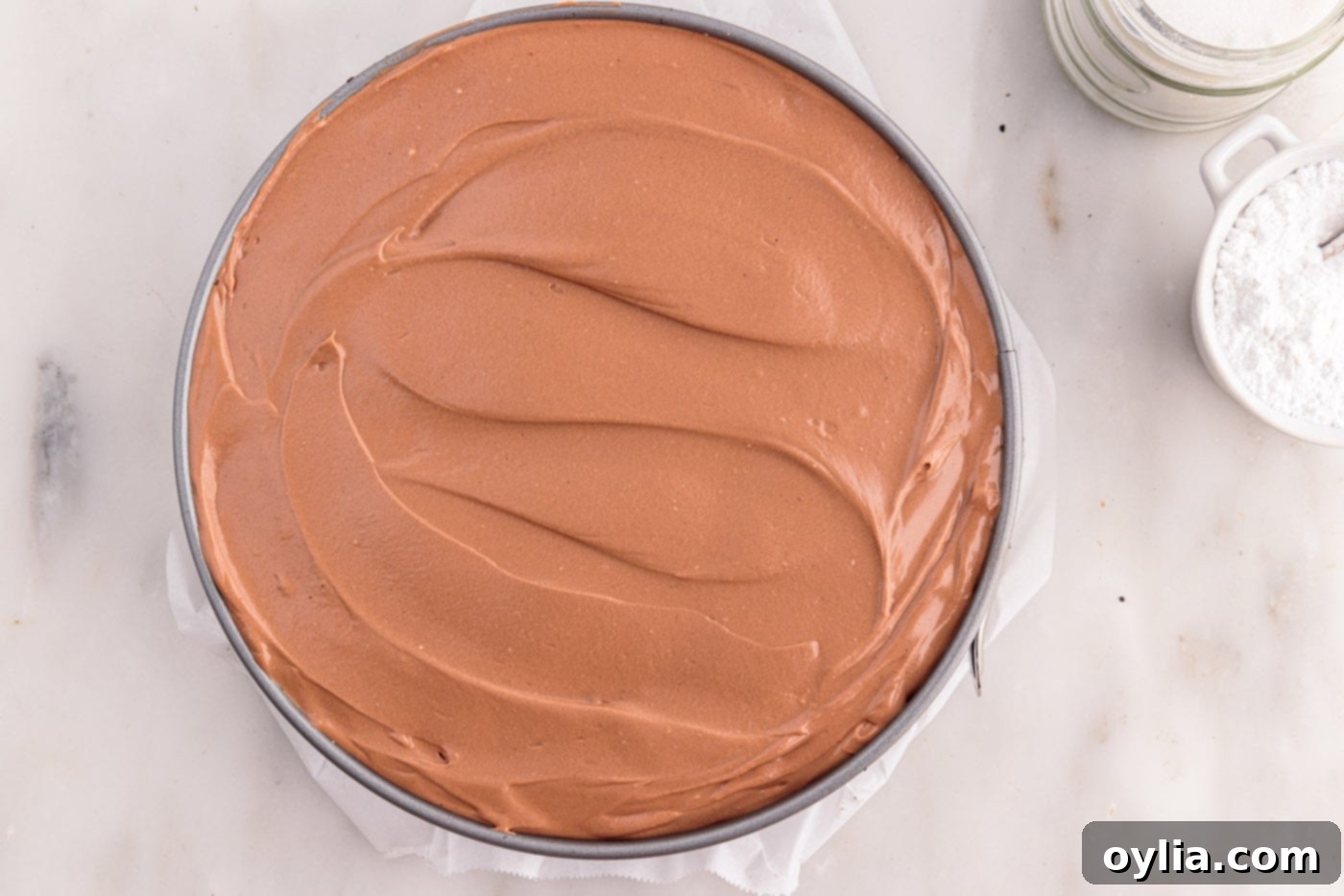 The easy no-bake chocolate cheesecake resting in a springform pan in the refrigerator, undergoing the essential chilling process to firm up.