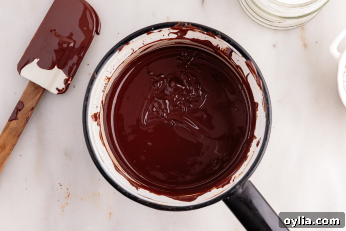 Melted chocolate being gently stirred in a double boiler over simmering water until it becomes a smooth and glossy liquid, indicating perfect consistency.