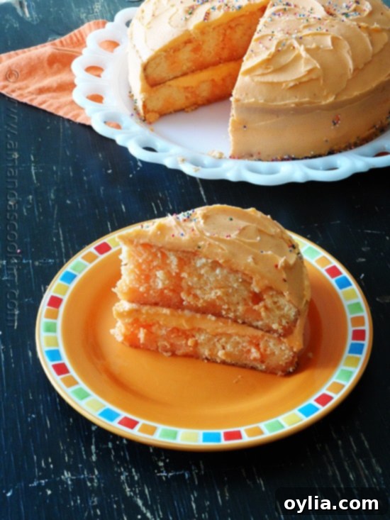 A vibrant slice of orange poke cake, showcasing its moist texture and bright frosting on an orange plate.