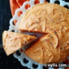 An overhead photo of an orange poke cake with a slice being removed, showing the vibrant interior.