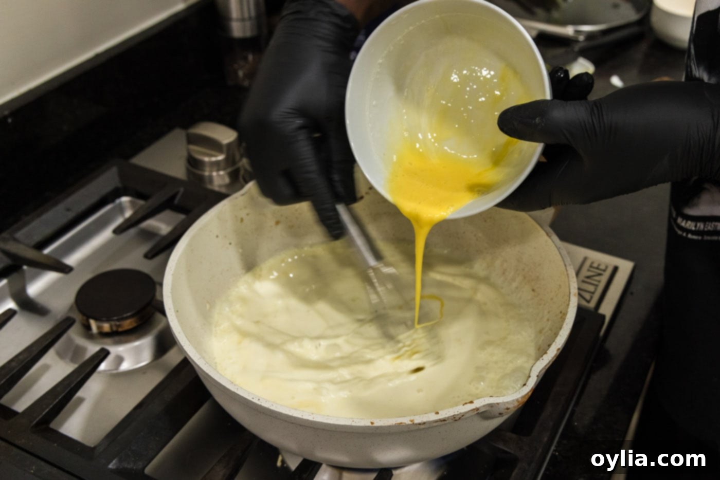 tempering eggs in heavy cream in a skillet