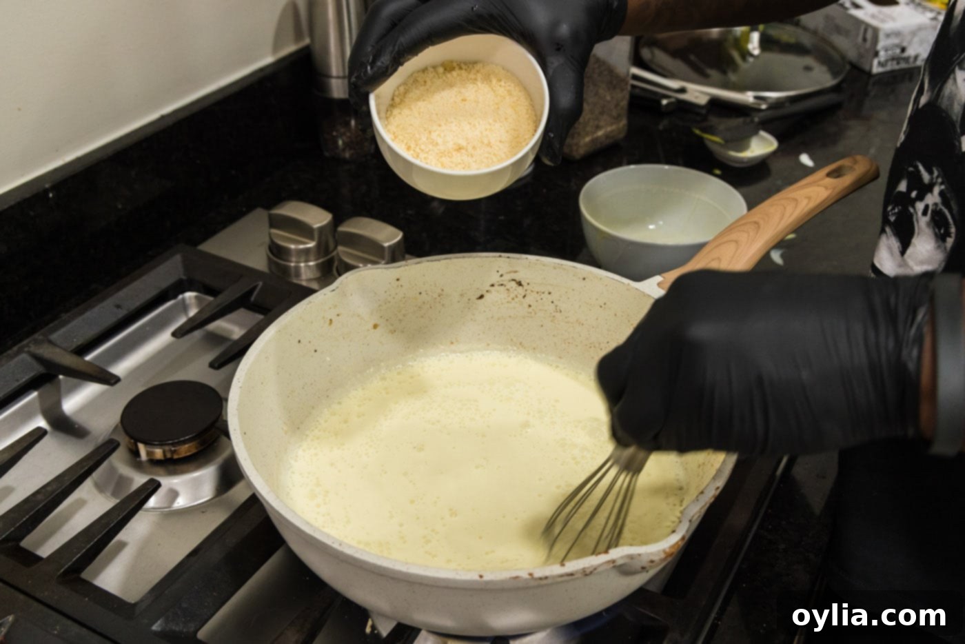 adding parmesan cheese to carbonara sauce in a skillet