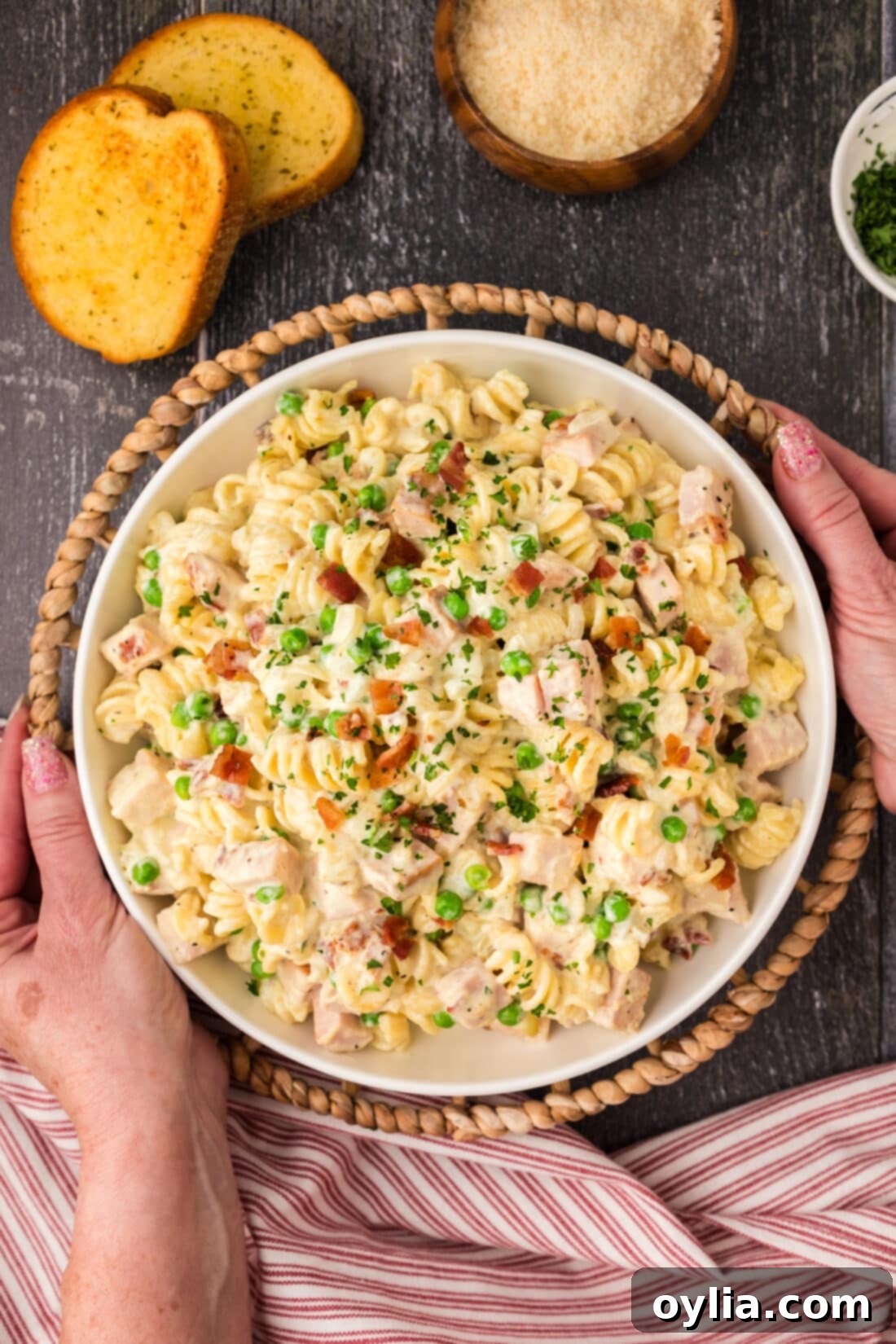 Hands holding a serving bowl of Turkey Carbonara