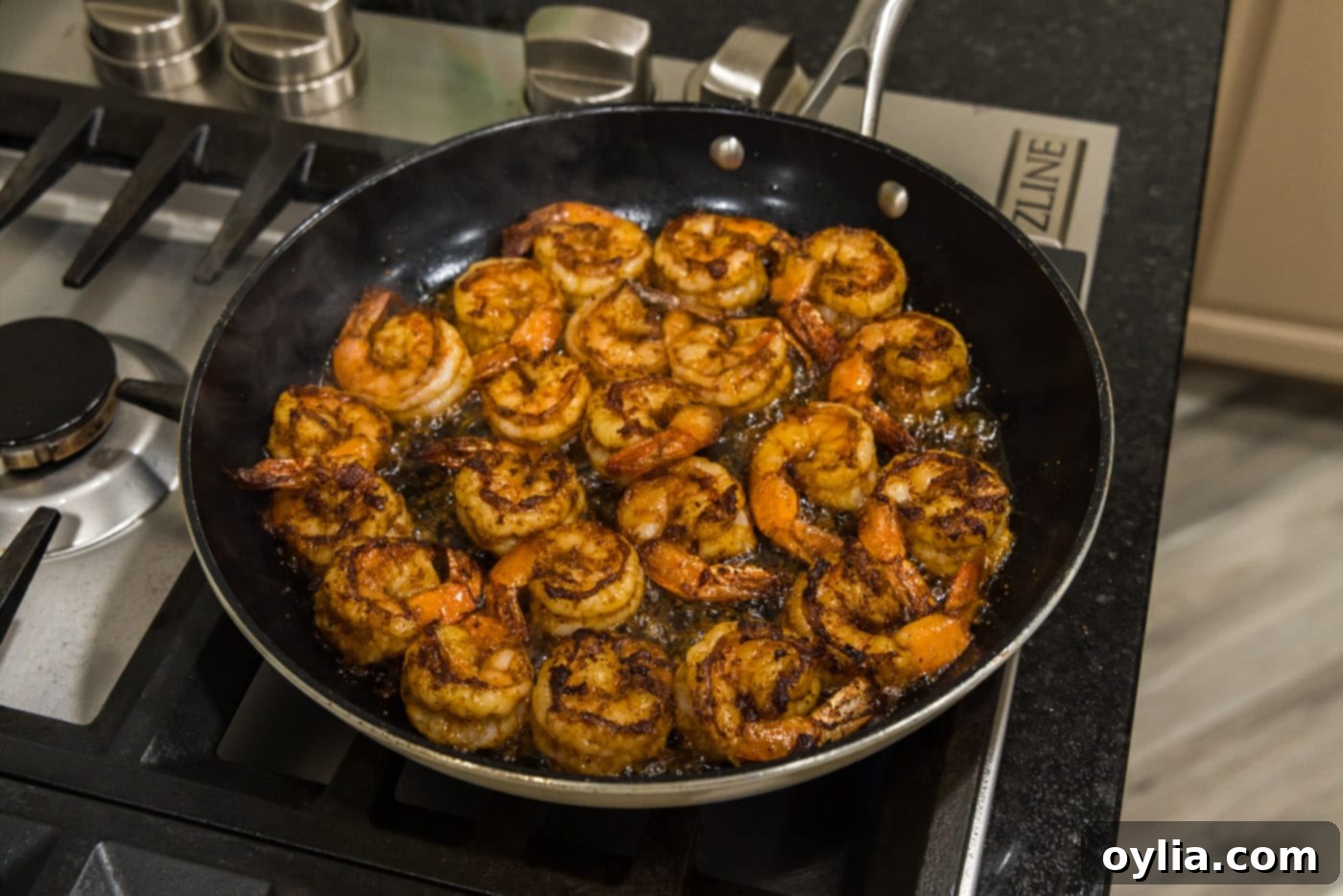 Cooked seasoned shrimp, perfectly seared and showing pink hues, still in the skillet