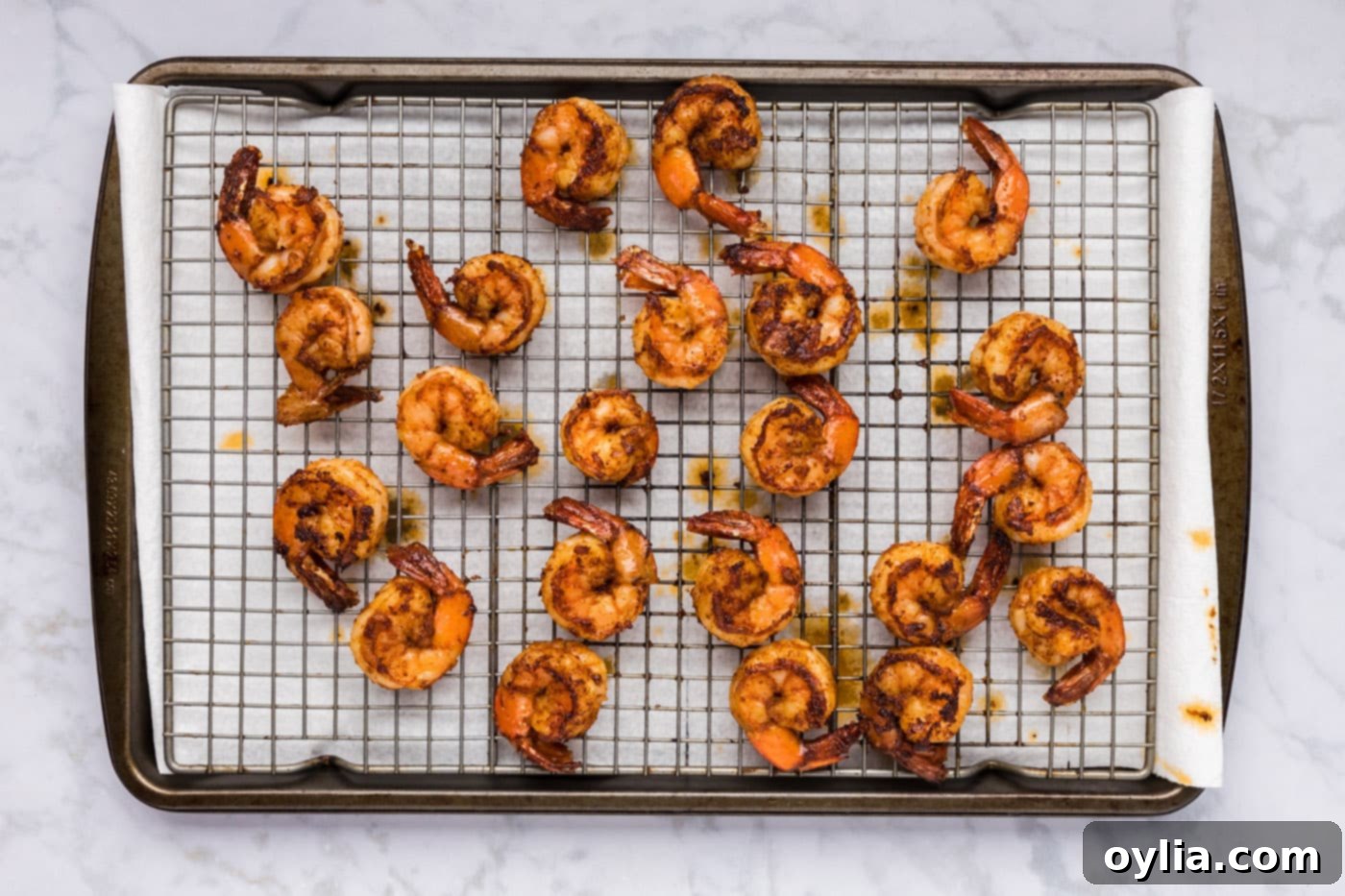 Cooked spicy shrimp resting on a wire rack after being removed from the skillet