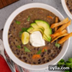 Bowl of Black Bean Soup topped with lime, sour cream, avocado and tortilla strips