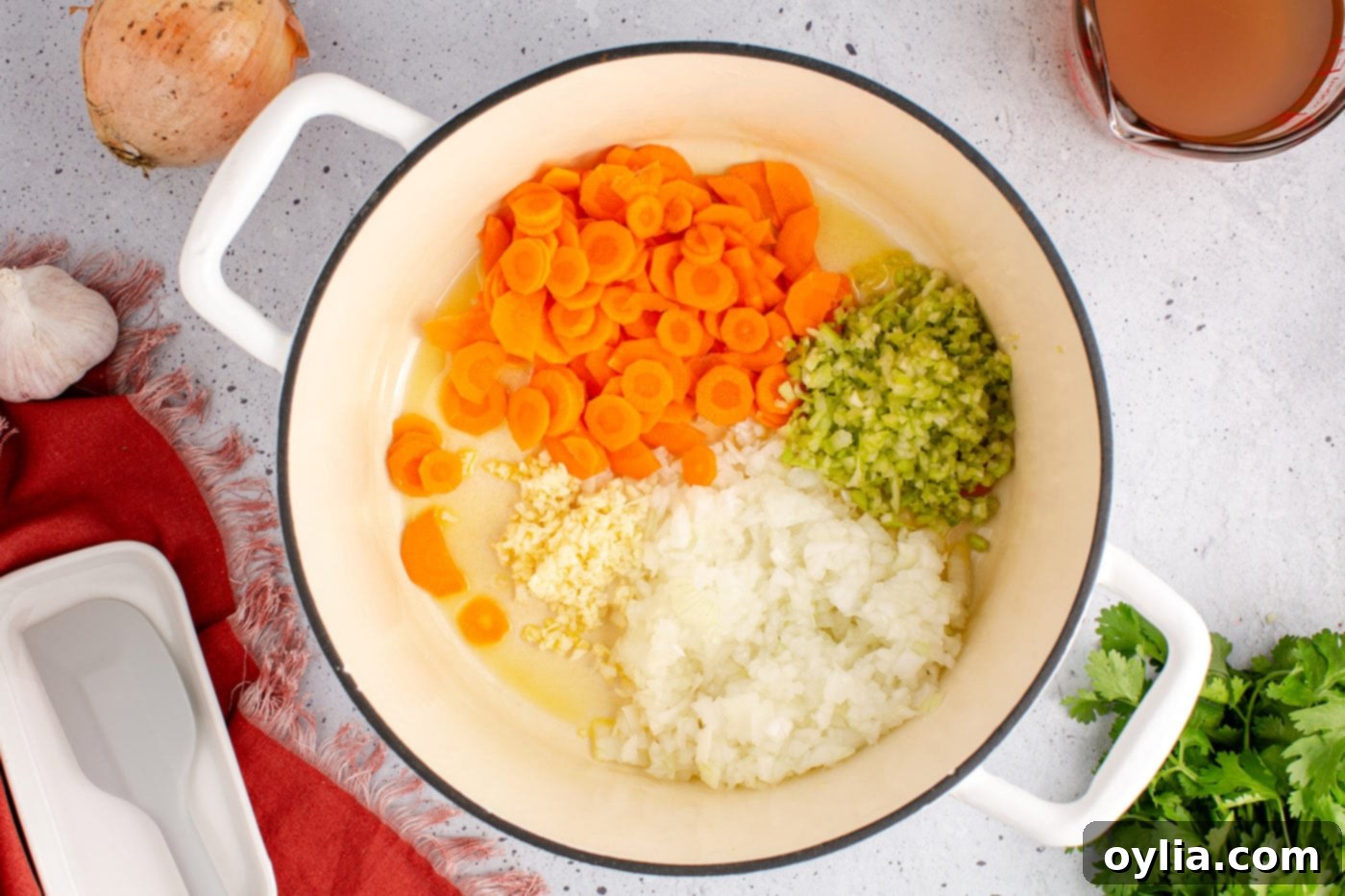Onion, carrots, celery, and garlic cooking in a soup pot with olive oil, beginning to soften.