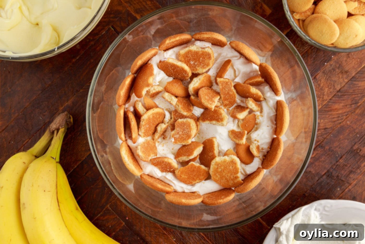 crushed nilla wafers added on top of whipped cream layer in a trifle bowl